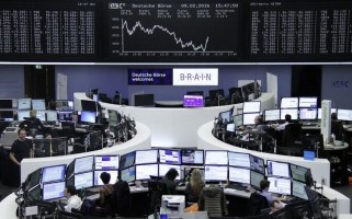 Traders work at their desks in front of the German share price index, DAX board, at the stock exchange in Frankfurt, Germany, February 9, 2016.     REUTERS/Staff/Remote